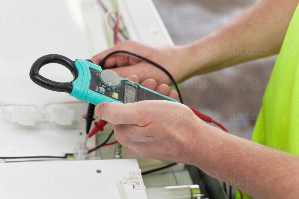 Image of Electrician testing power board with a multimeter - Austockphoto
