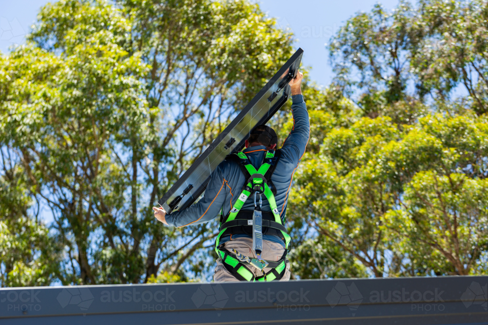 Image of Electrician tradie worker man on roof of house carrying solar ...