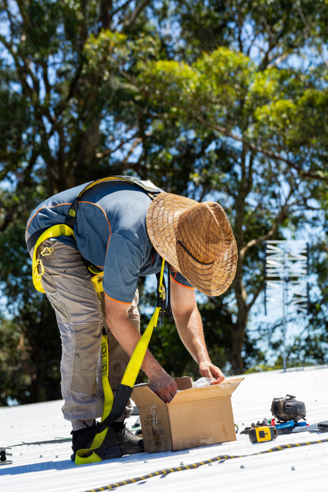 Image of Electrician tradie worker man on roof of suburban house ...