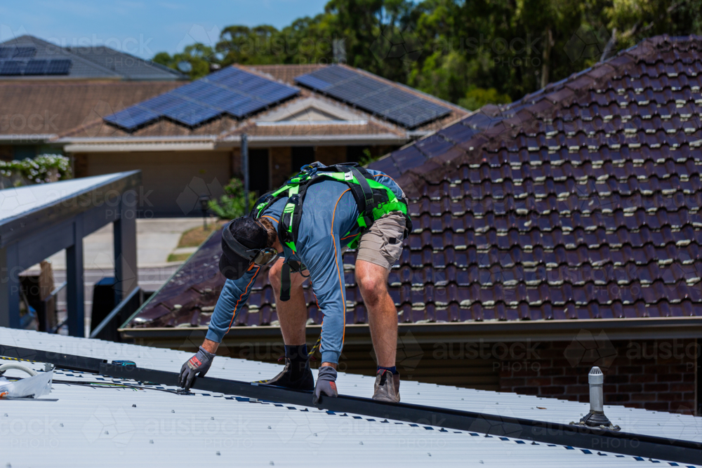 Image of Electrician tradie worker man on roof of suburban house ...