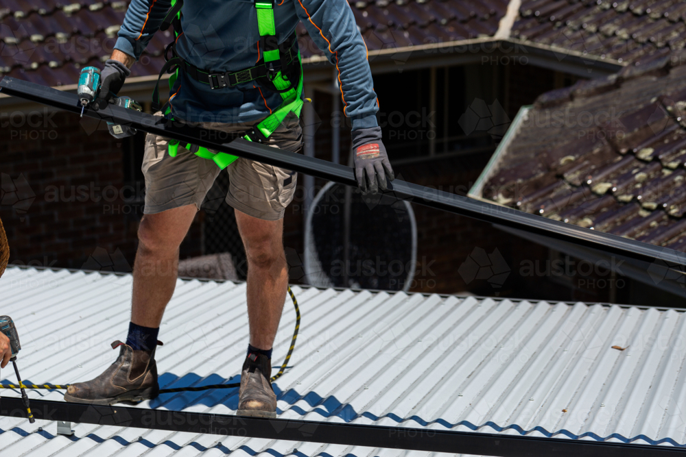 Image of Electrician tradie worker man on roof of suburban house ...