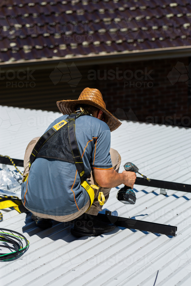 Image of Electrician tradie worker man on roof of suburban house ...