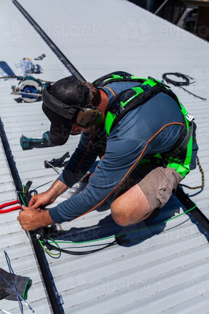 Image of Electrician tradie worker man on roof of suburban house ...