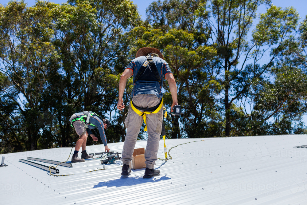 Image of Electrician tradie worker men on roof of suburban house ...