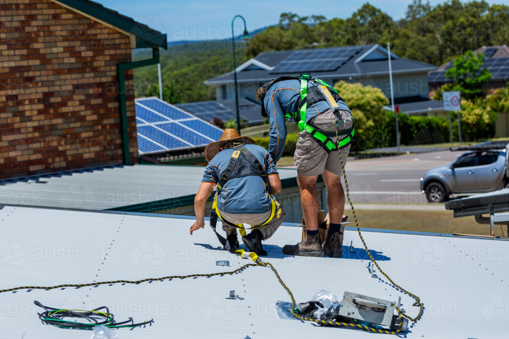 Image of Electrician tradie worker men on roof of suburban house ...