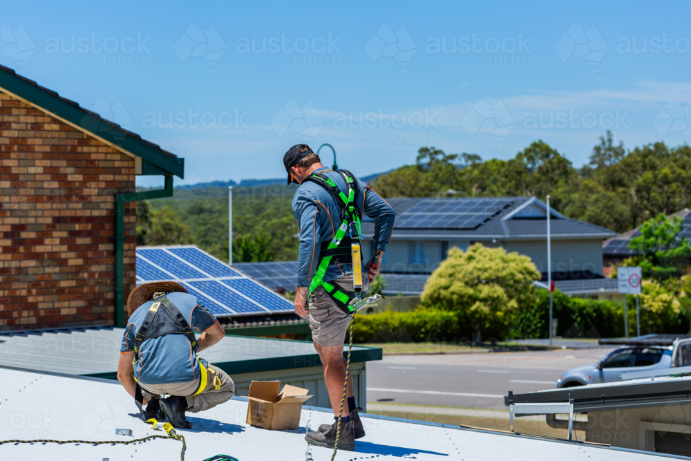 Image of Electrician tradie worker men on roof of suburban house ...