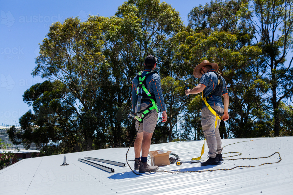 Image of Electrician tradie workers on house roof discussing installing ...