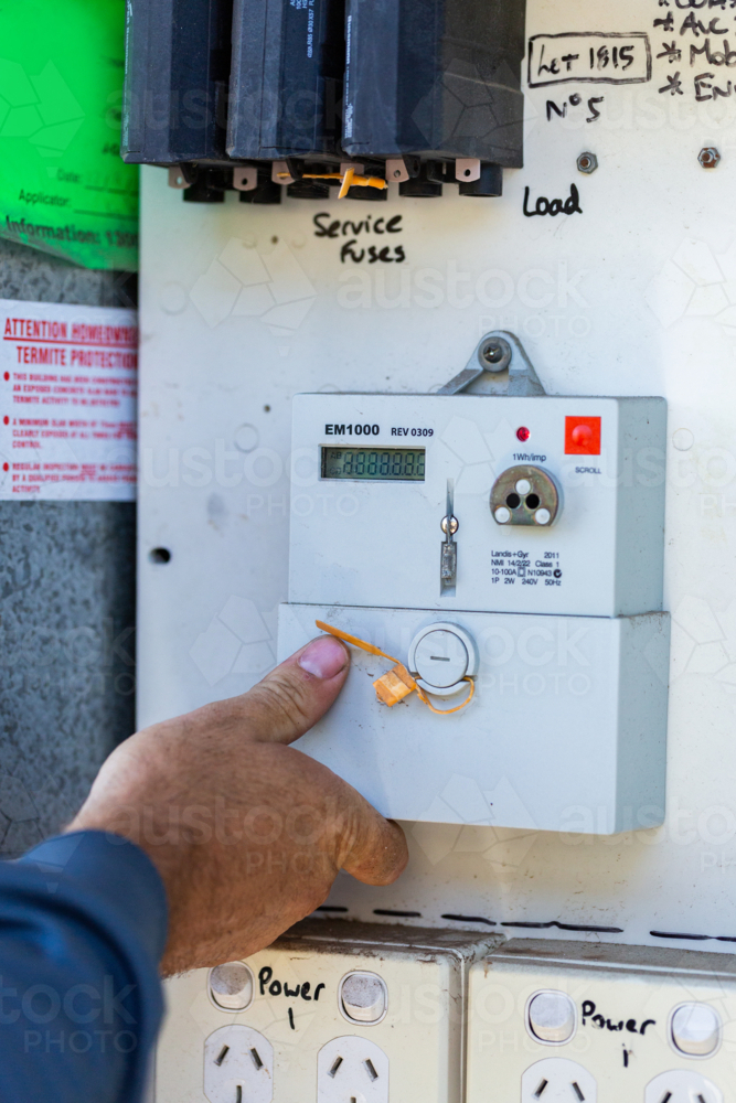 Electrician tradie working on outside breaker box power box - Australian Stock Image