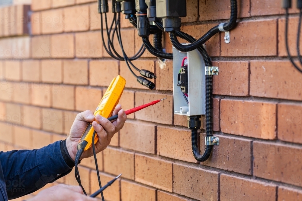 Electrician using multimeter tool to check power in solar system installation : Austockphoto Electrician using multimeter tool to check power in solar system installation - Australian Stock Image
