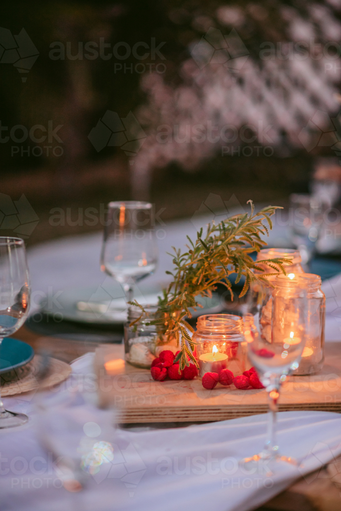 Elegant outdoor dinner setting with candles and fresh decorations in a warm evening atmosphere - Australian Stock Image