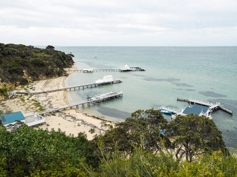 Elevated view of jetty and boat sheds at a tranquil bay - Australian Stock Image