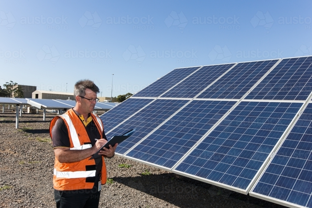 employee taking notes at a solar panel plant - Australian Stock Image