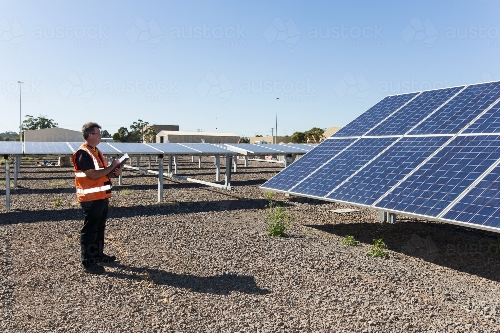 Employee taking notes at a solar panel plant - Australian Stock Image