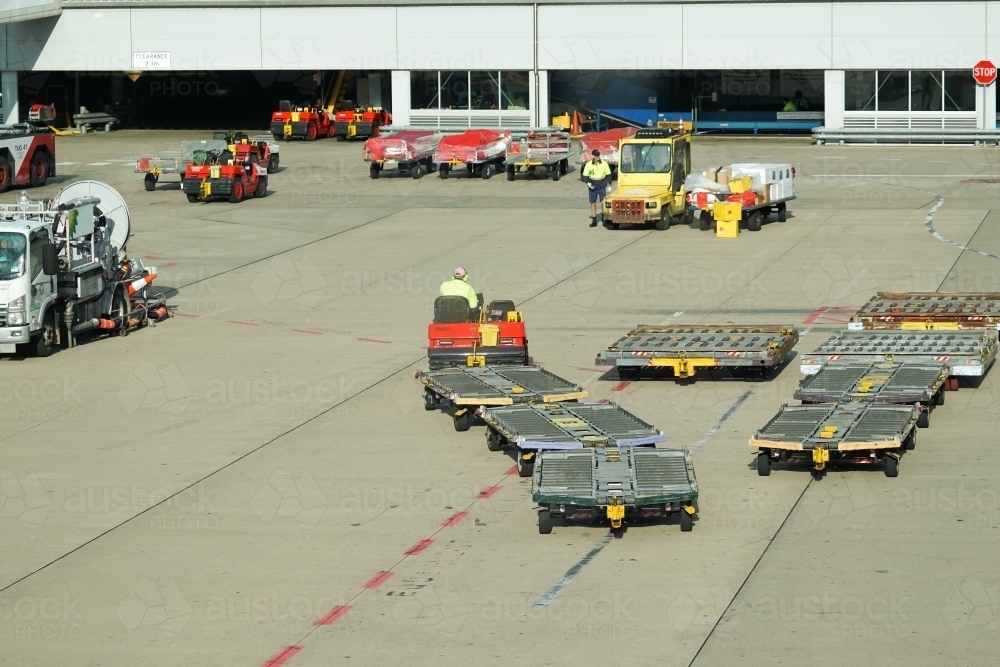 Empty baggage carts on airport tarmac - Australian Stock Image