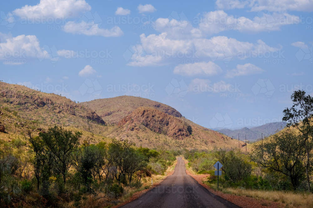 Empty country Road winding into the distant ochre sandstone ranges - Australian Stock Image