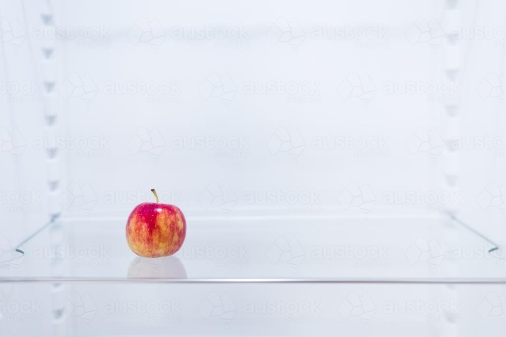 empty fridge with just 1 apple - Australian Stock Image