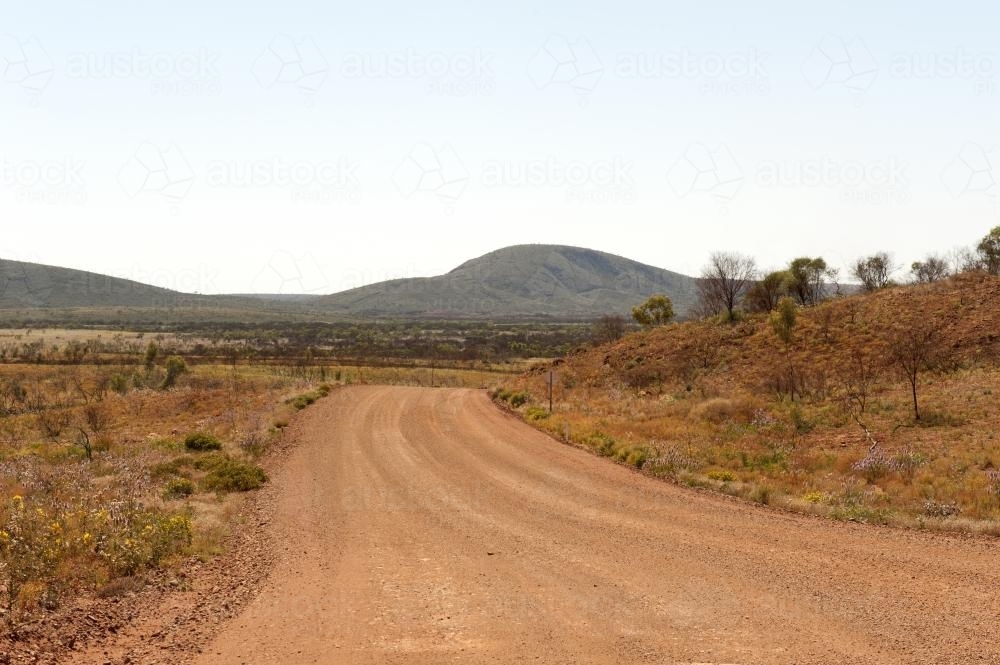 Empty Pilbara dirt road and landscape in early morning - Australian Stock Image