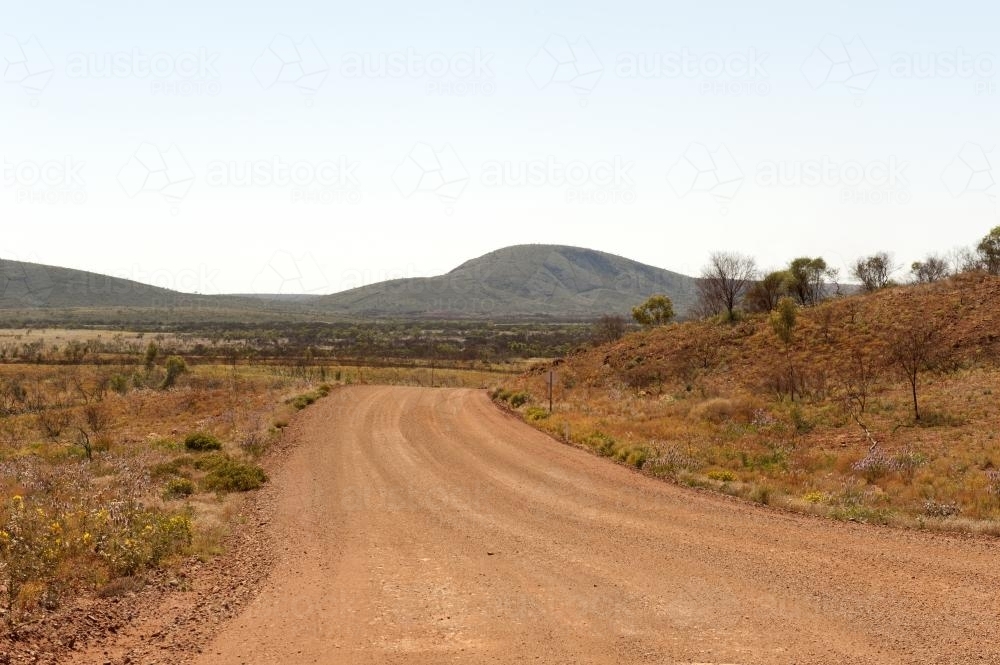 Empty Pilbara dirt road and landscape in early morning - Australian Stock Image