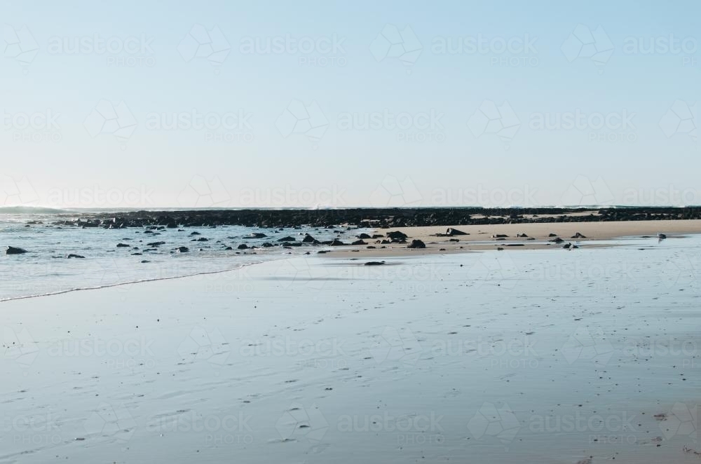 Empty, rocky beach with clear sky - Australian Stock Image