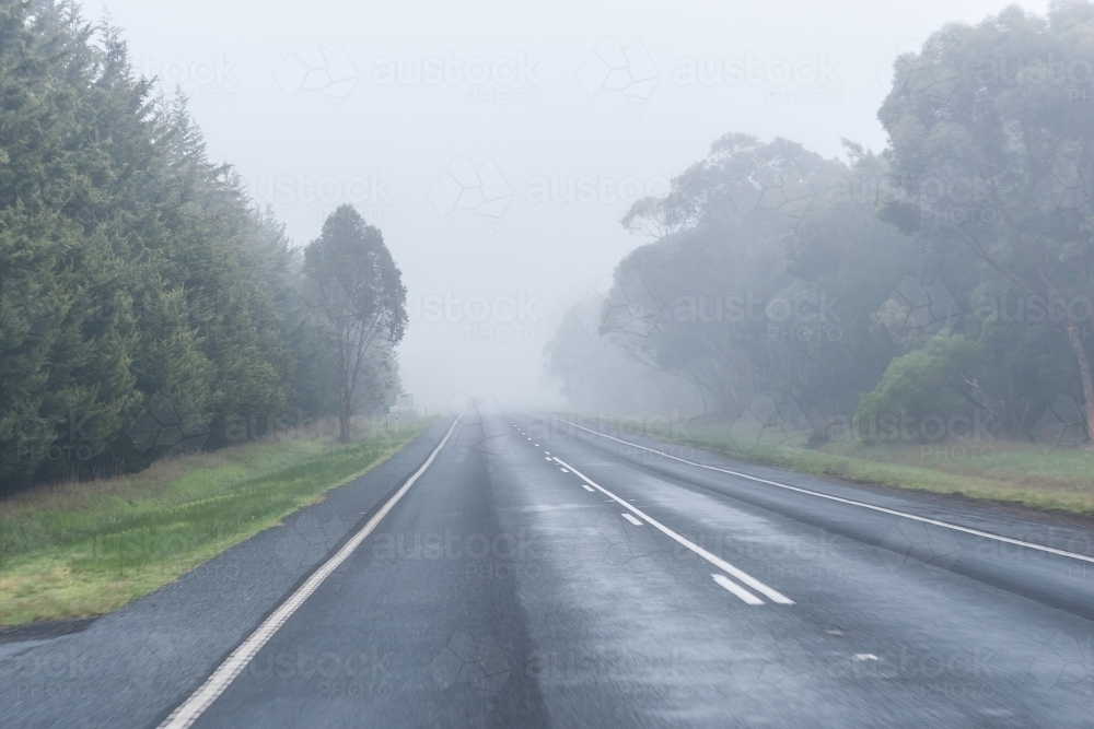 Empty sealed road leading into fog - Australian Stock Image