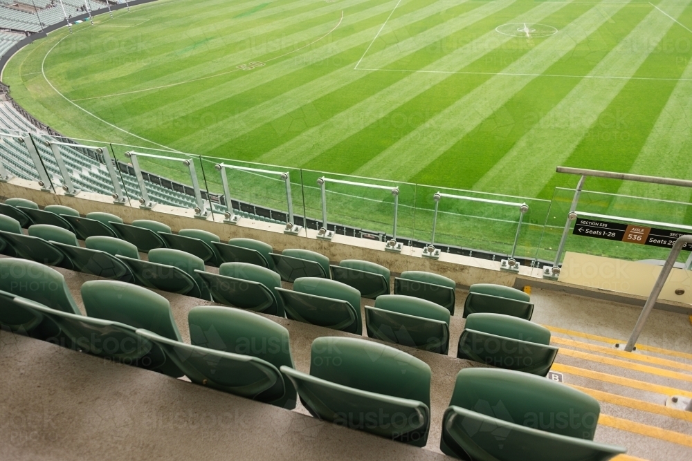 Empty stadium seats and a green afl oval - Australian Stock Image