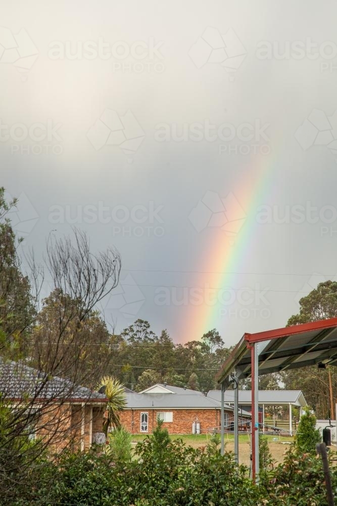 End of a rainbow over houses - Australian Stock Image
