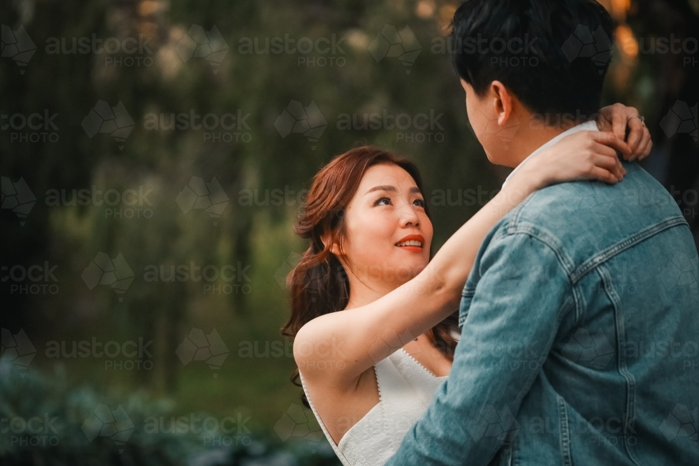 Engaged couple embracing in tree lined avenue in Melbourne's Treasury Gardens - Australian Stock Image