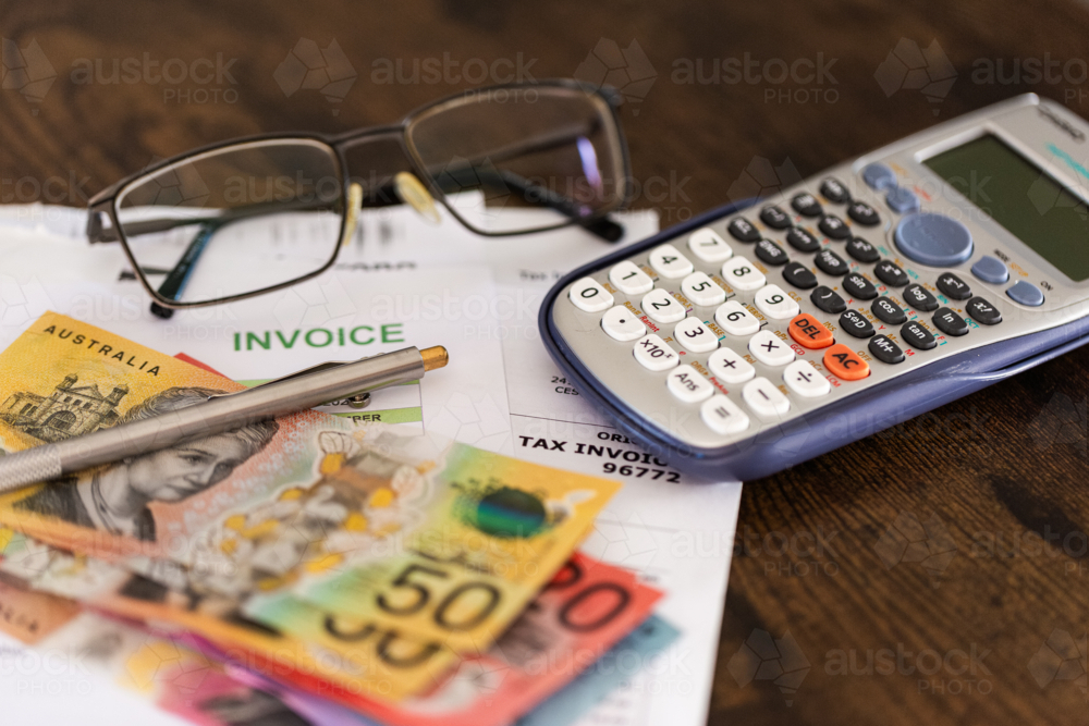 EOFY tax time concept with Australian banknotes and invoices beside calculator and glasses - Australian Stock Image