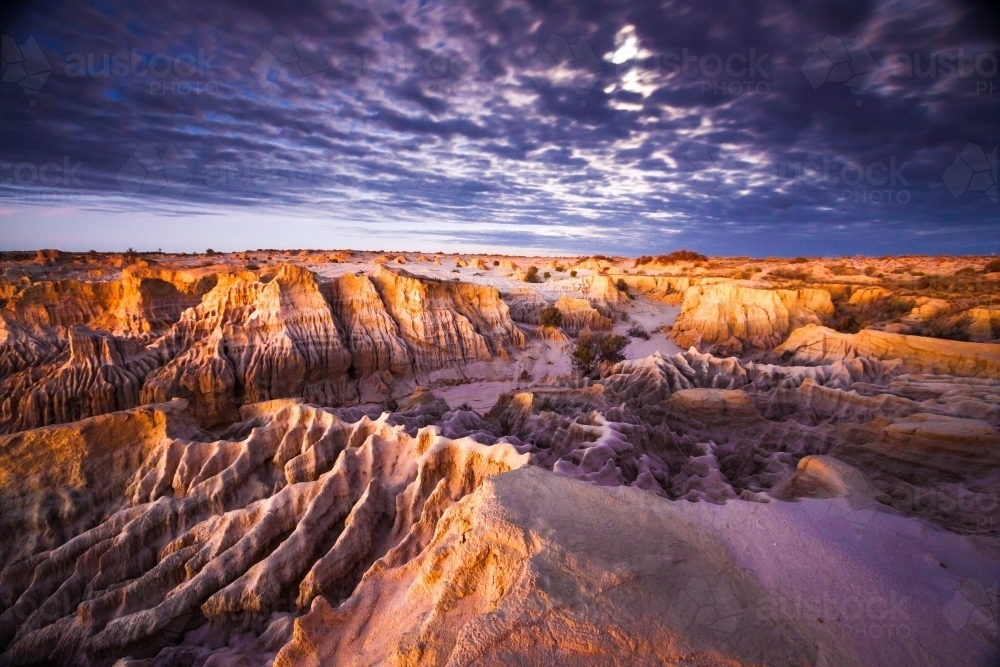 Eroded landscape of middens and creek beds at sunset : Austockphoto Eroded landscape of middens and creek beds at sunset - Australian Stock Image