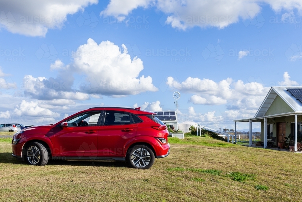 EV car on farm in country, buildings in the background have solar panels on rooves - Australian Stock Image