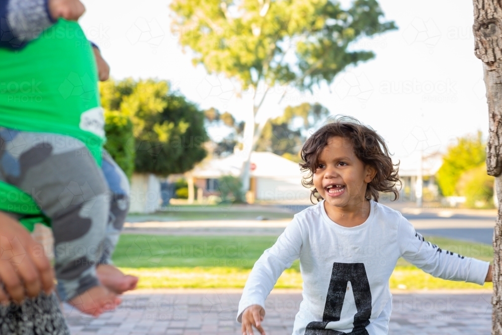 Excited child running with mother and baby nearby - Australian Stock Image
