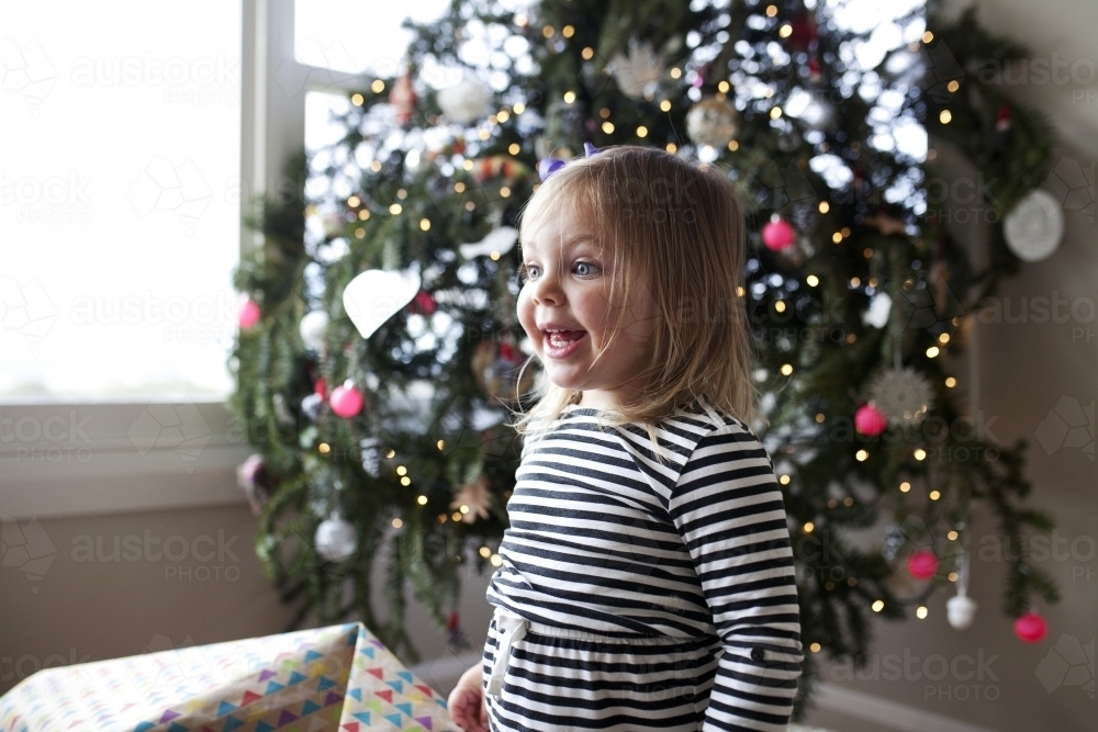Excited young girl in front of Christmas tree - Australian Stock Image