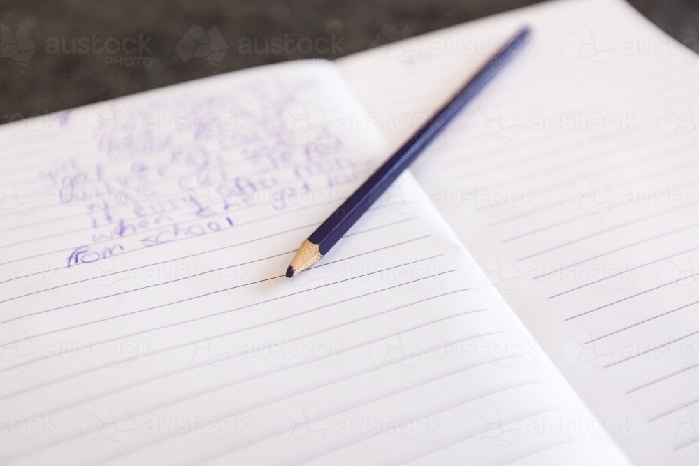 Exercise book with child's writing and pencil - Australian Stock Image