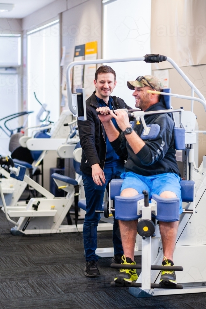 exercise therapy equipment at physiotherapy clinic with smiling man using it at treatment - Australian Stock Image