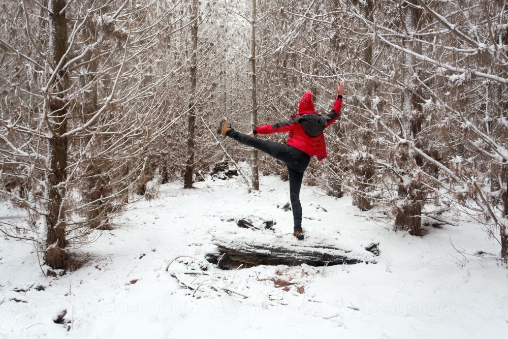 Exercising and stretching in the snow while balanced on log - Australian Stock Image