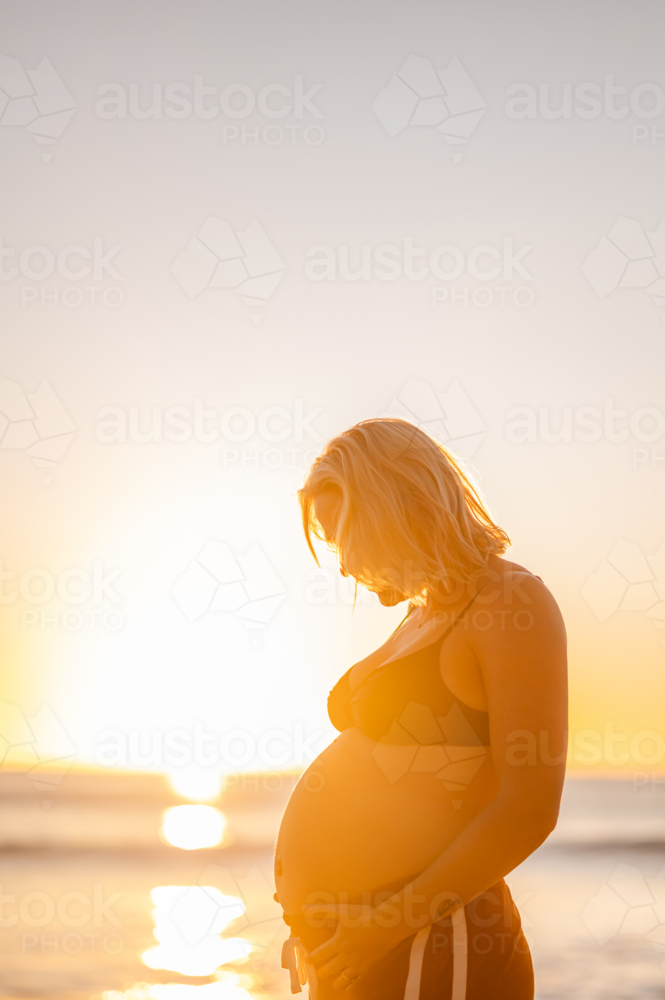 Expecting mother at Manly Beach during sunrise, in a moment of joy and love - Australian Stock Image
