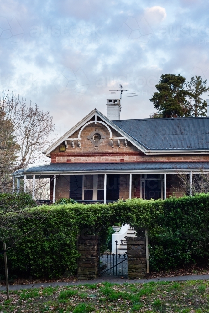 exterior of sandstone house with gabled roof and chimney - Australian Stock Image