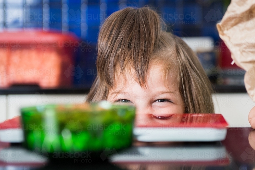 Eyes of daughter looking over bench - cooking at home - Australian Stock Image
