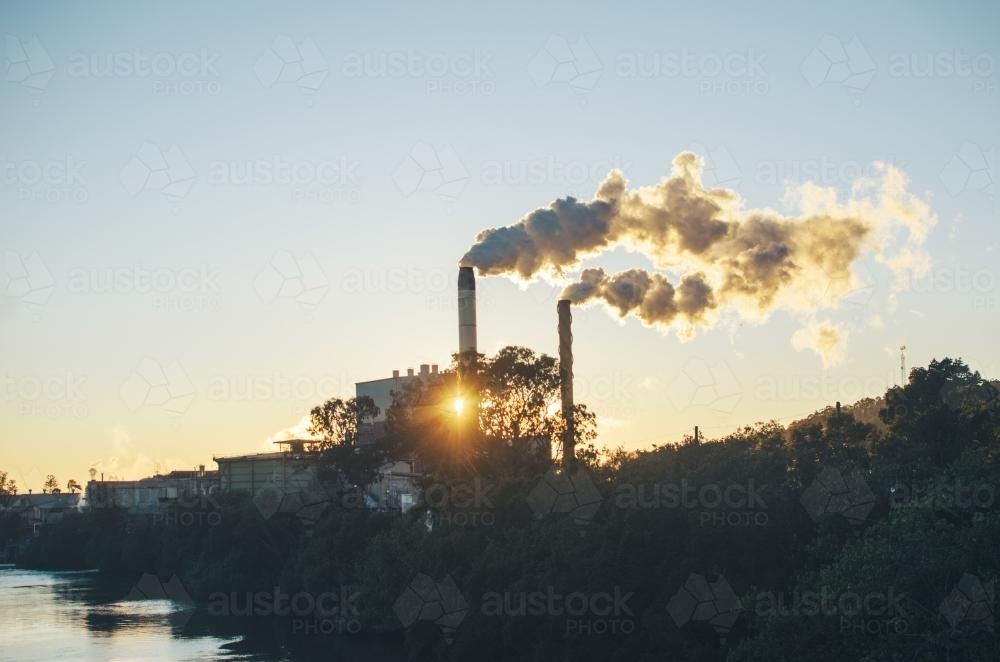 Factory at sunrise along river - Australian Stock Image