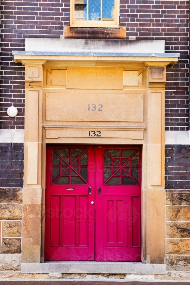 Faded red doors in stone and brick building - Australian Stock Image