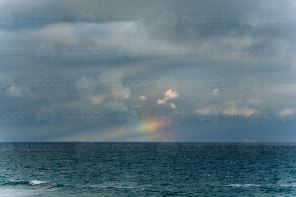 Faint rainbow glowing above the ocean horizon - Australian Stock Image
