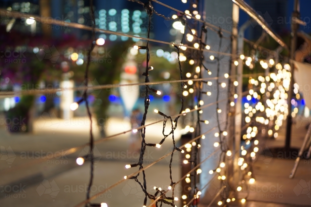 Fairy lights along a railing with city background - Australian Stock Image