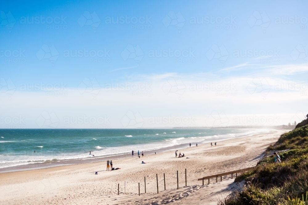 Families spending time near the entrance to a long sandy beach on a summers day with blue skies. - Australian Stock Image