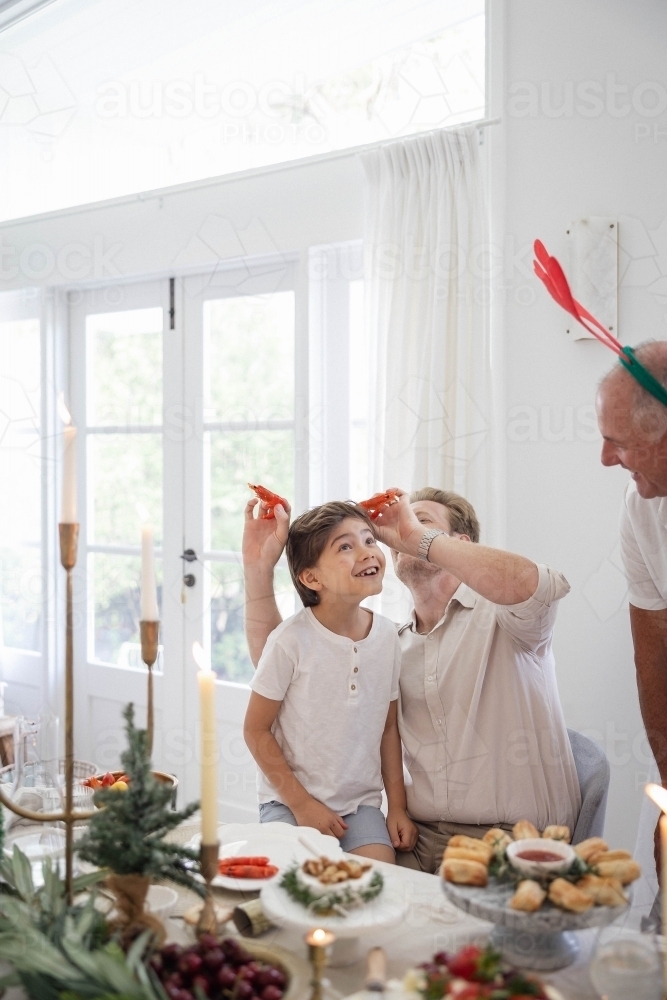 Family at Christmas table making jokes with prawns - Australian Stock Image