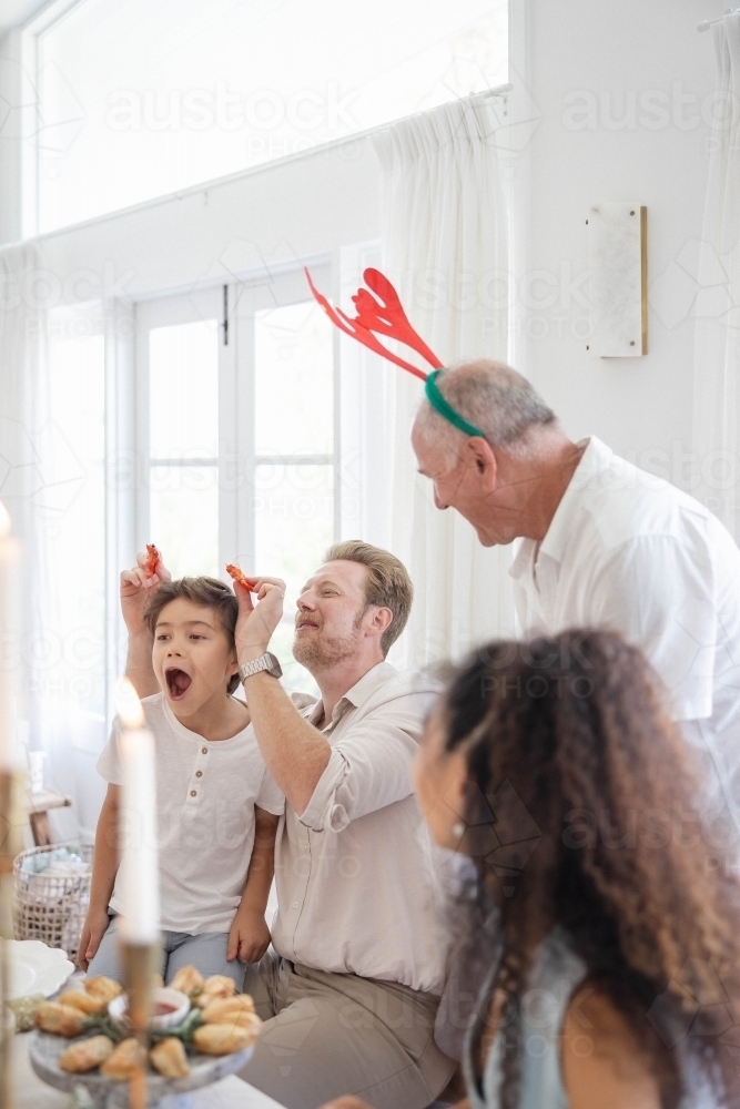 Family at Christmas table making jokes with prawns - Australian Stock Image