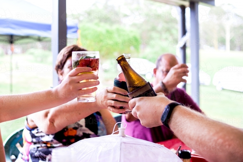 Family clink their alcoholic drinks to say cheers at Christmas party. - Australian Stock Image