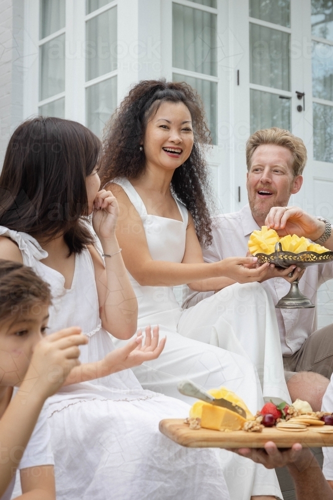 Family eating snacks on backyard stairs - Australian Stock Image