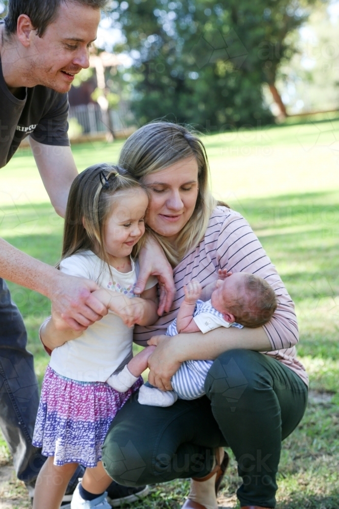 Family group with a new-born baby in a green, shady park - Australian Stock Image