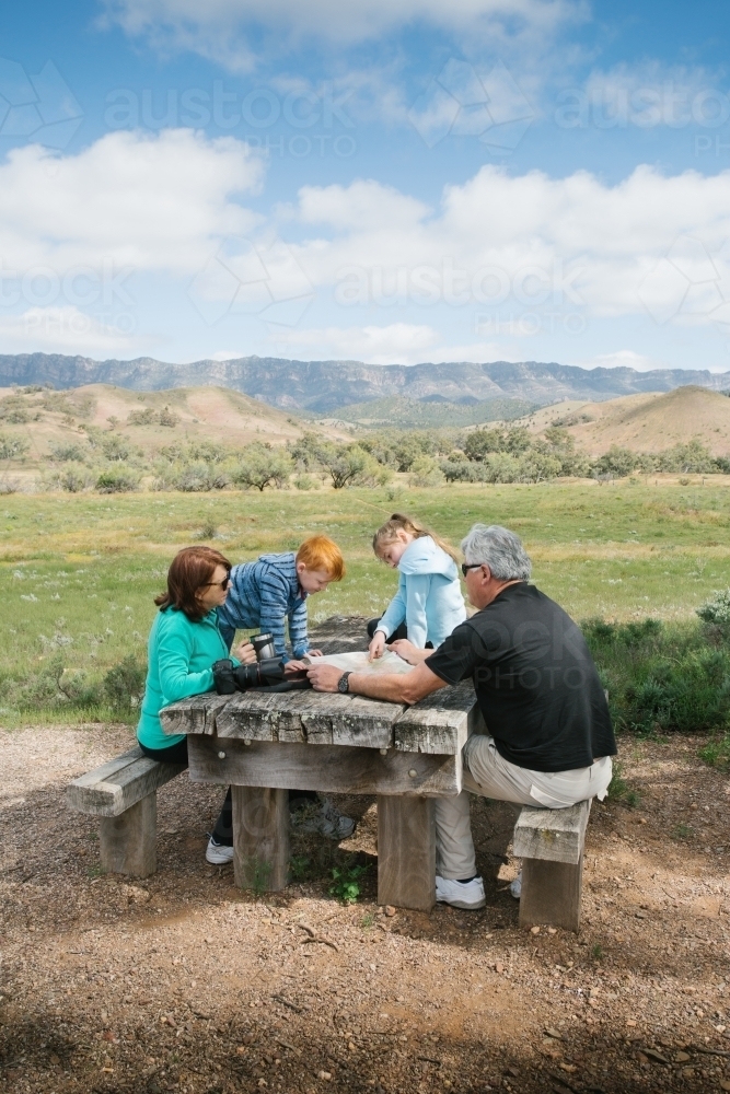 Family having a rest at a wooden table in the outback - Australian Stock Image