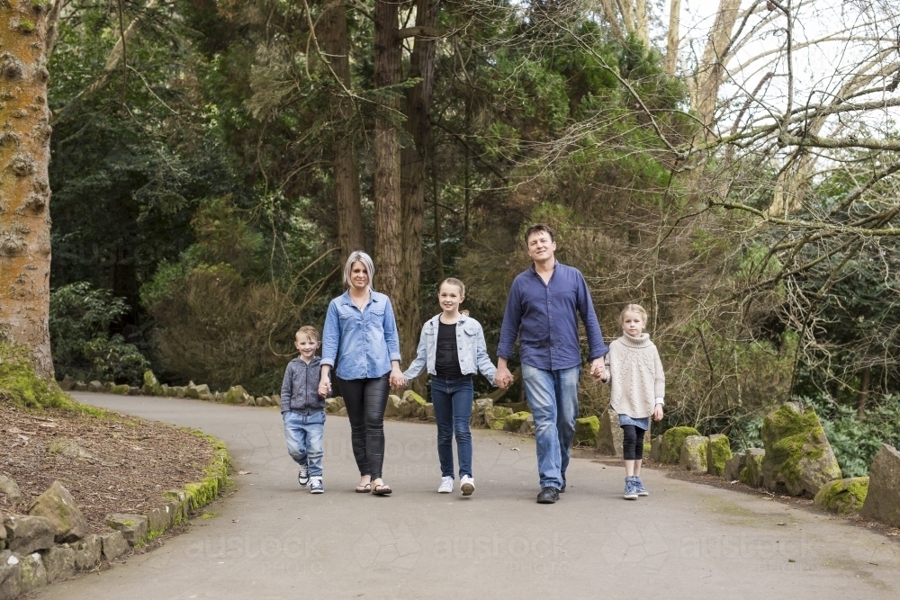 Family holding hands and walking down path - Australian Stock Image
